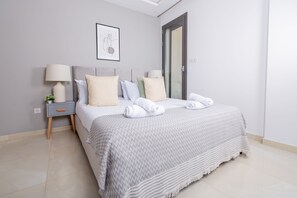 Ein ordentlich eingerichtetes Schlafzimmer mit einem Bett, Nachttischen und einer Tür.