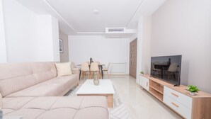 Una sala moderna con sofá, mesa de centro, mueble para la televisión y comedor.