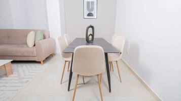 A dining area with a table, chairs, a sofa, and a rug.