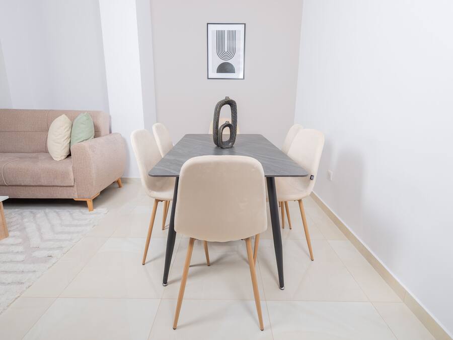 A dining area with a table, chairs, a sofa, and a rug.