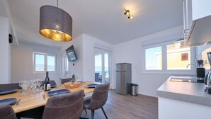 A modern kitchen with a dining area, large windows, and a view of the sea. - Queen's Lodge Mastrinka by Litto (Mastrinka)