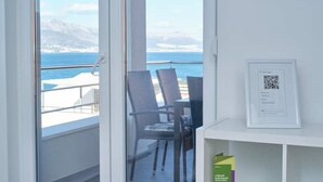 A balcony with a view of the sea and mountains, two chairs, and a QR code on the wall. - Queen's Lodge Mastrinka by Litto (Mastrinka)