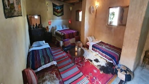 A cozy, rustic room with two beds, a small round table, and a sofa.
