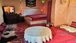 A cozy room with a bed, a small round table, a dresser, and a mirror.