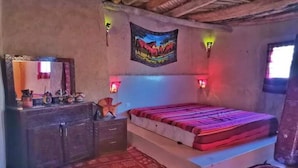 A bedroom with a bed, a dresser, a mirror, and a wall-mounted tapestry.