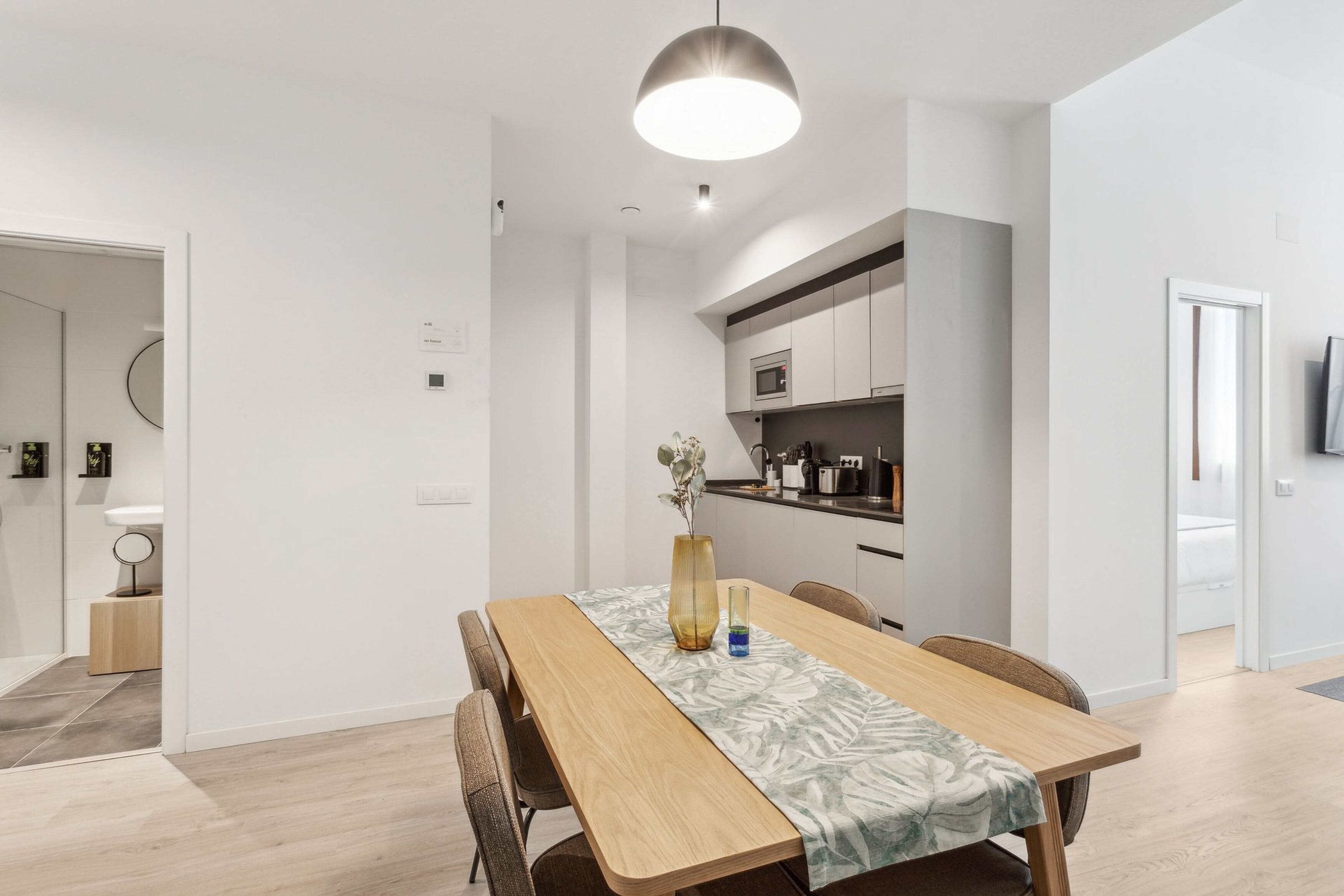 Un comedor moderno con una mesa de madera, sillas y un florero.