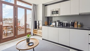 A modern kitchen with a built-in microwave, stainless steel appliances, and a sliding glass door leading to a balcony with outdoor furniture. - Limehome Valencia Calle de Cadiz (Valencia)
