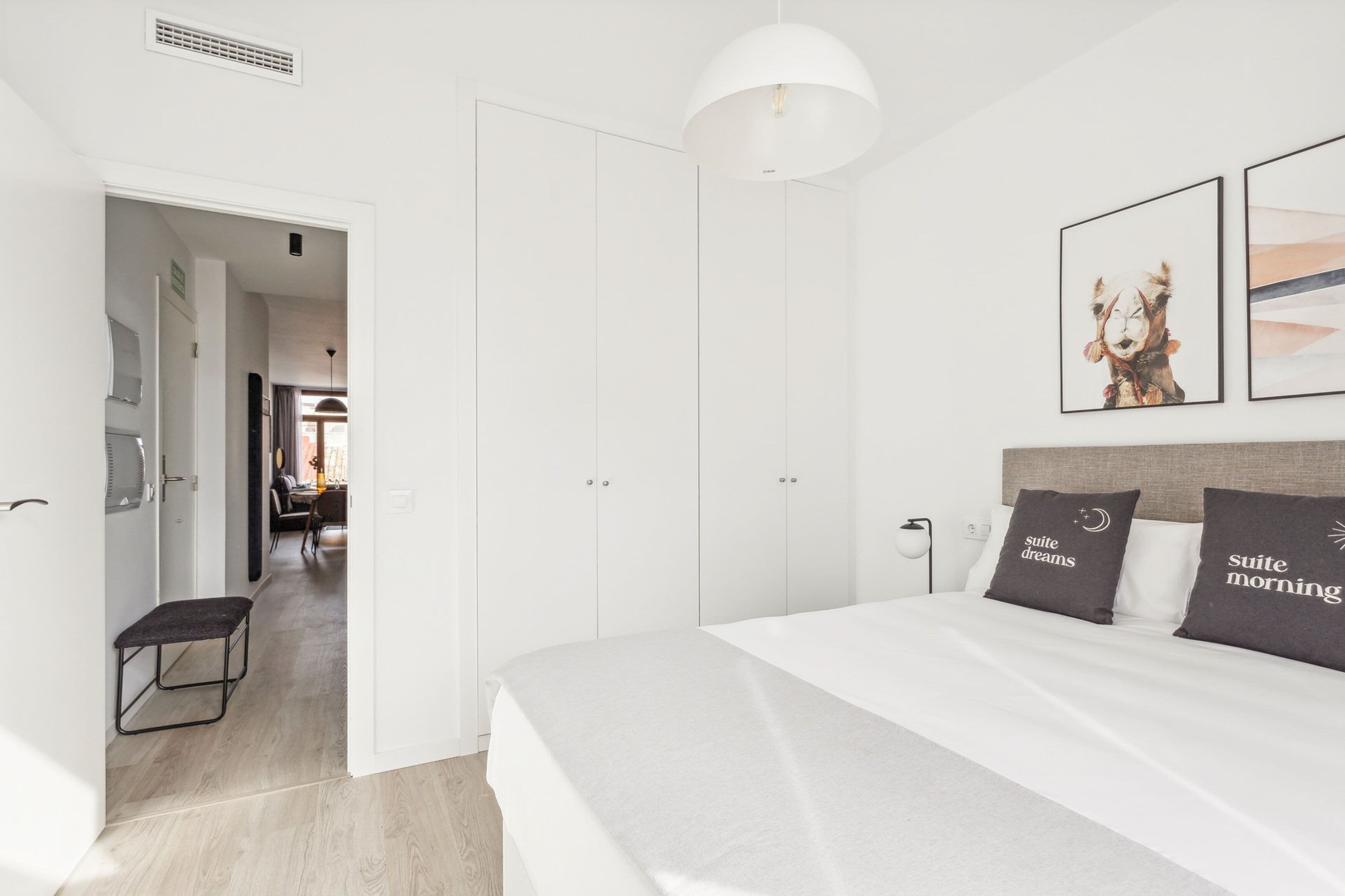 Una habitación de hotel moderna con una cama grande, paredes blancas y un diseño minimalista.