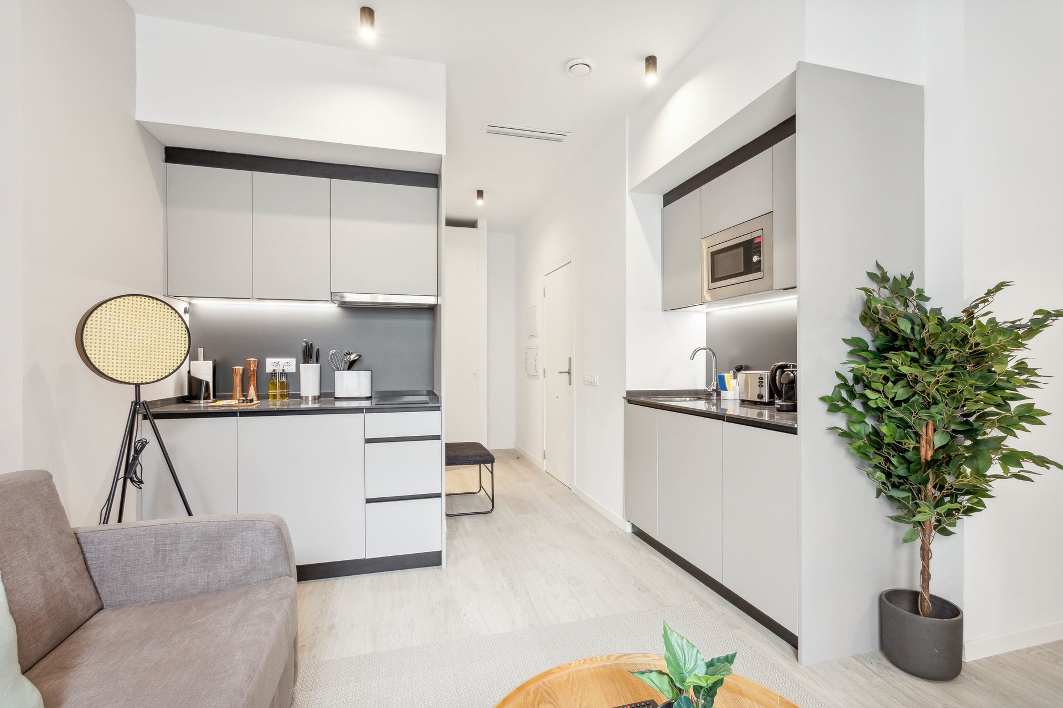 A modern kitchen with white cabinetry, a microwave, and a potted plant.