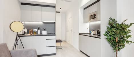 A modern kitchen with white cabinetry, a microwave, and a potted plant.