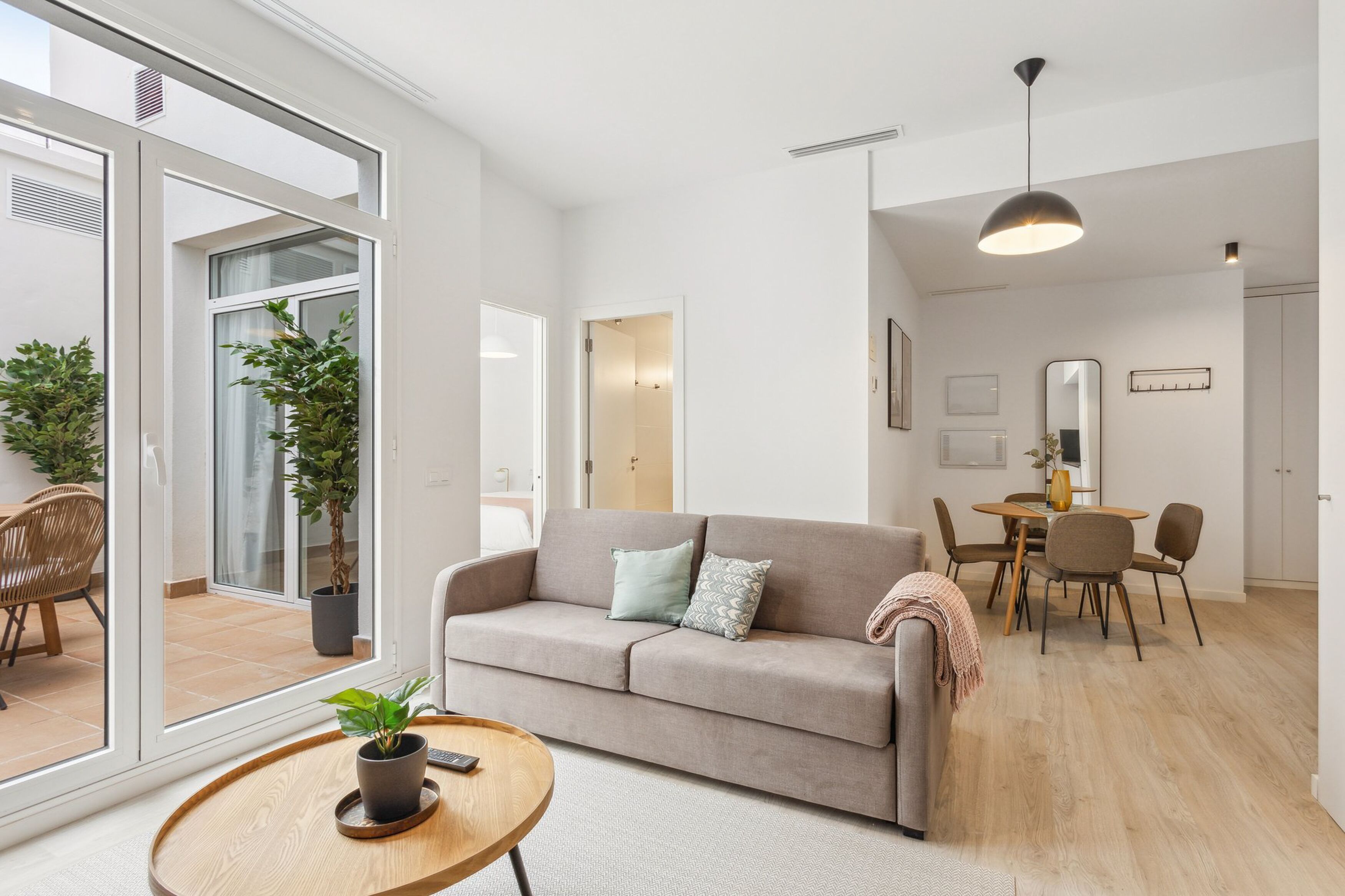 A modern living room with a sofa, coffee table, and dining area.