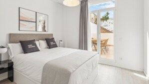 A modern hotel room with a large bed, a desk, and a view of the outside balcony. - Limehome Valencia Calle de Cadiz (Valencia)