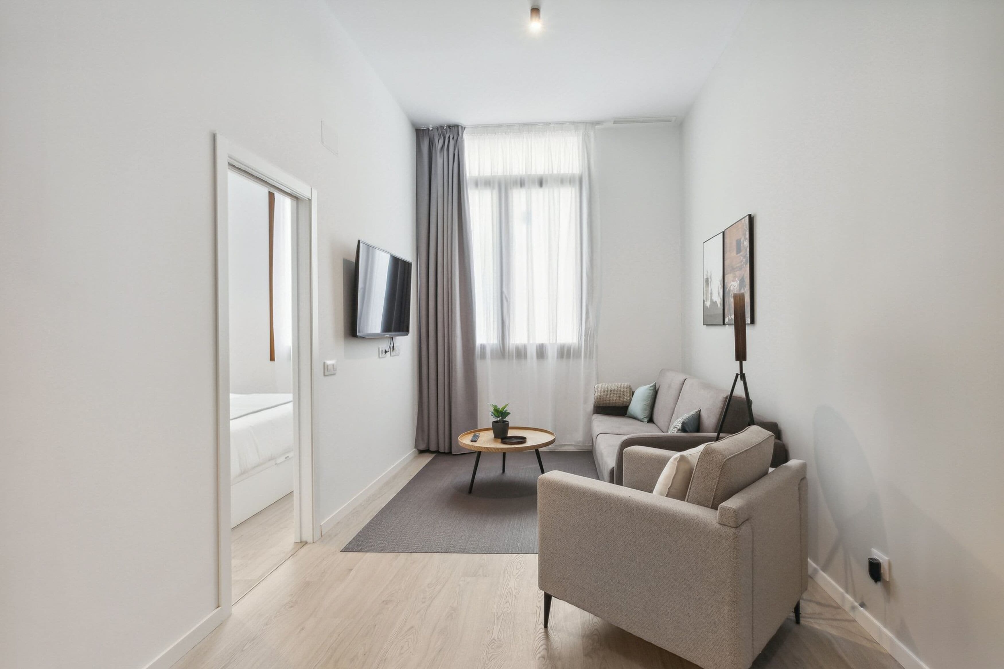 Un salon moderne avec un canapé, une table basse et un téléviseur fixé au mur.