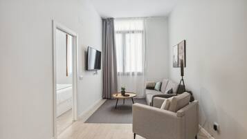 Een moderne woonkamer met een bank, een salontafel en een televisie die aan de muur is bevestigd.