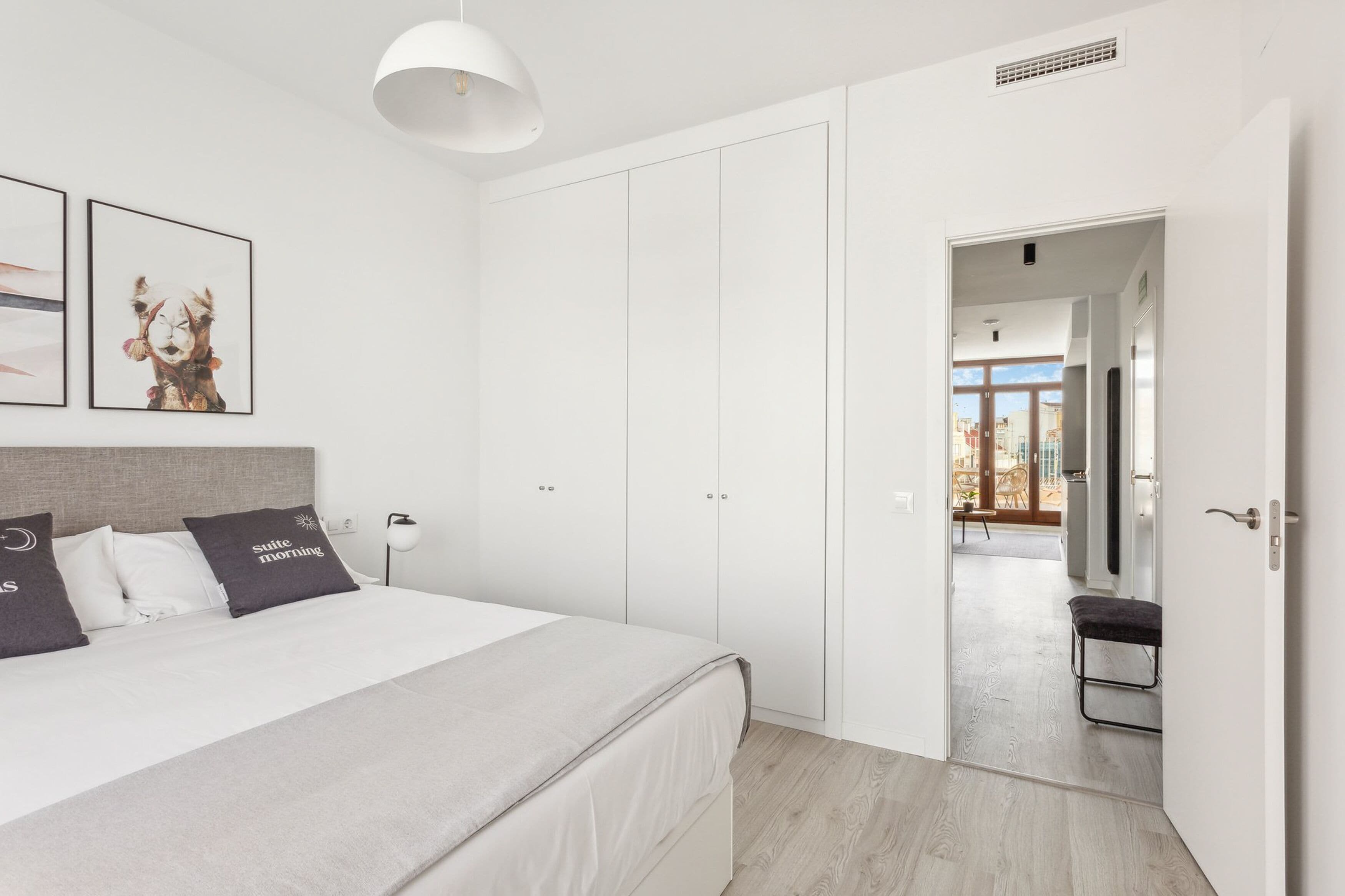 Ein modernes Schlafzimmer mit einem großen Bett, einem Kleiderschrank und Blick ins Freie.