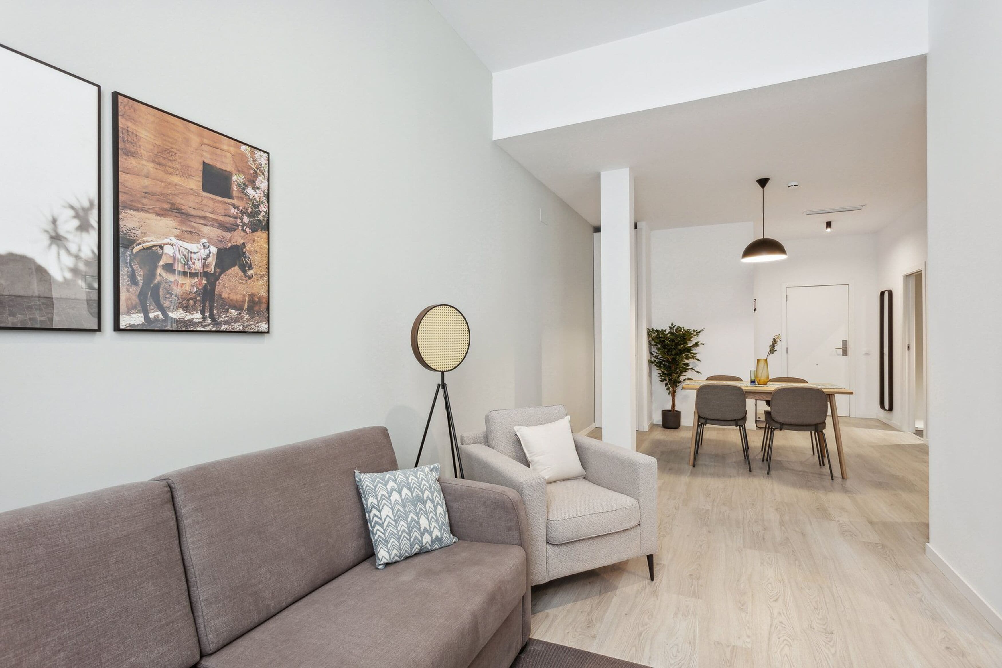 Una sala de estar moderna con un sofá, una mesa de comedor con sillas y una lámpara de pie.