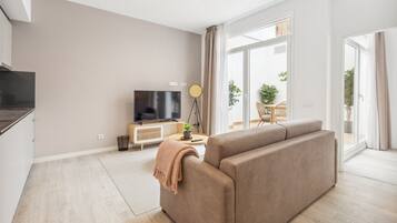 Een moderne woonkamer met een bank, televisie en een eethoek met een tafel en stoelen.