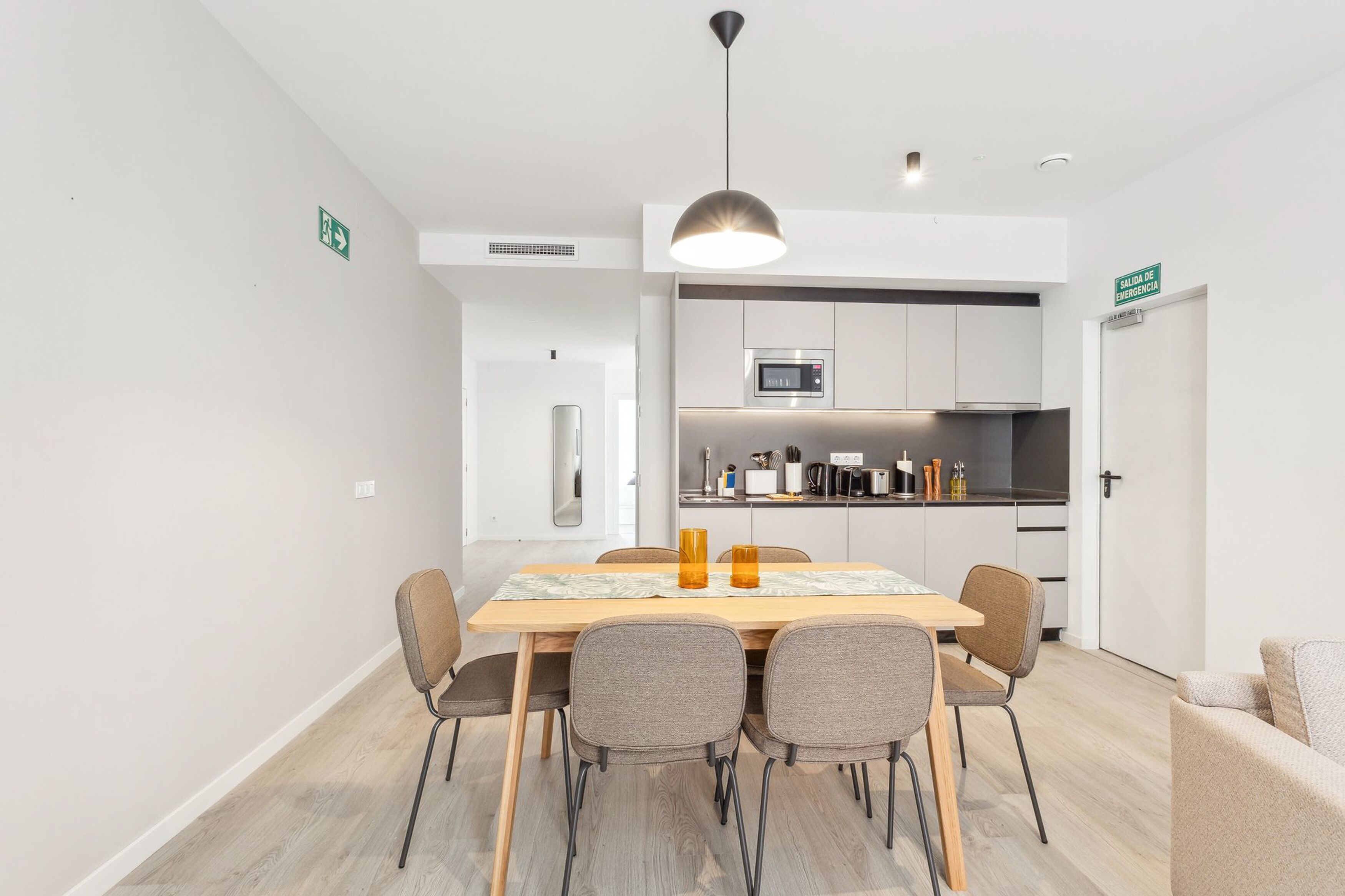 A modern kitchen with white cabinets, a microwave, and a sink.