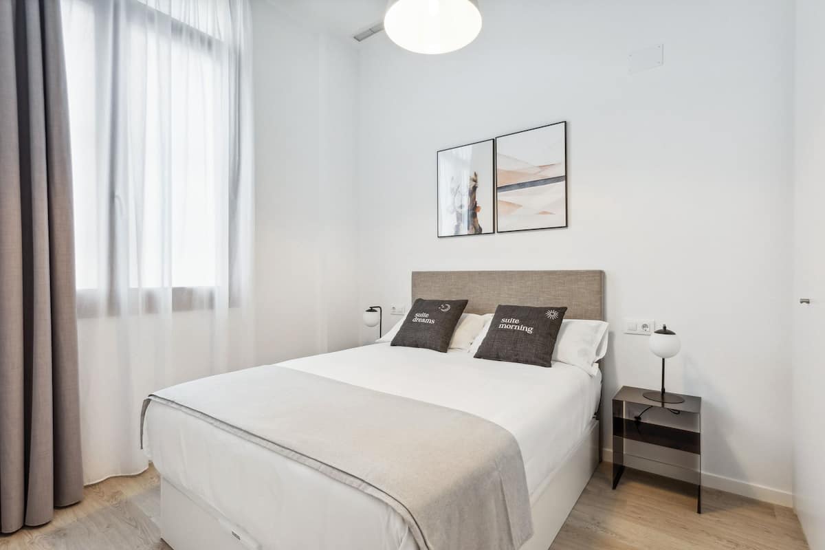 A neatly arranged hotel room with a large bed, two bedside tables, a nightstand, and a wall-mounted picture.