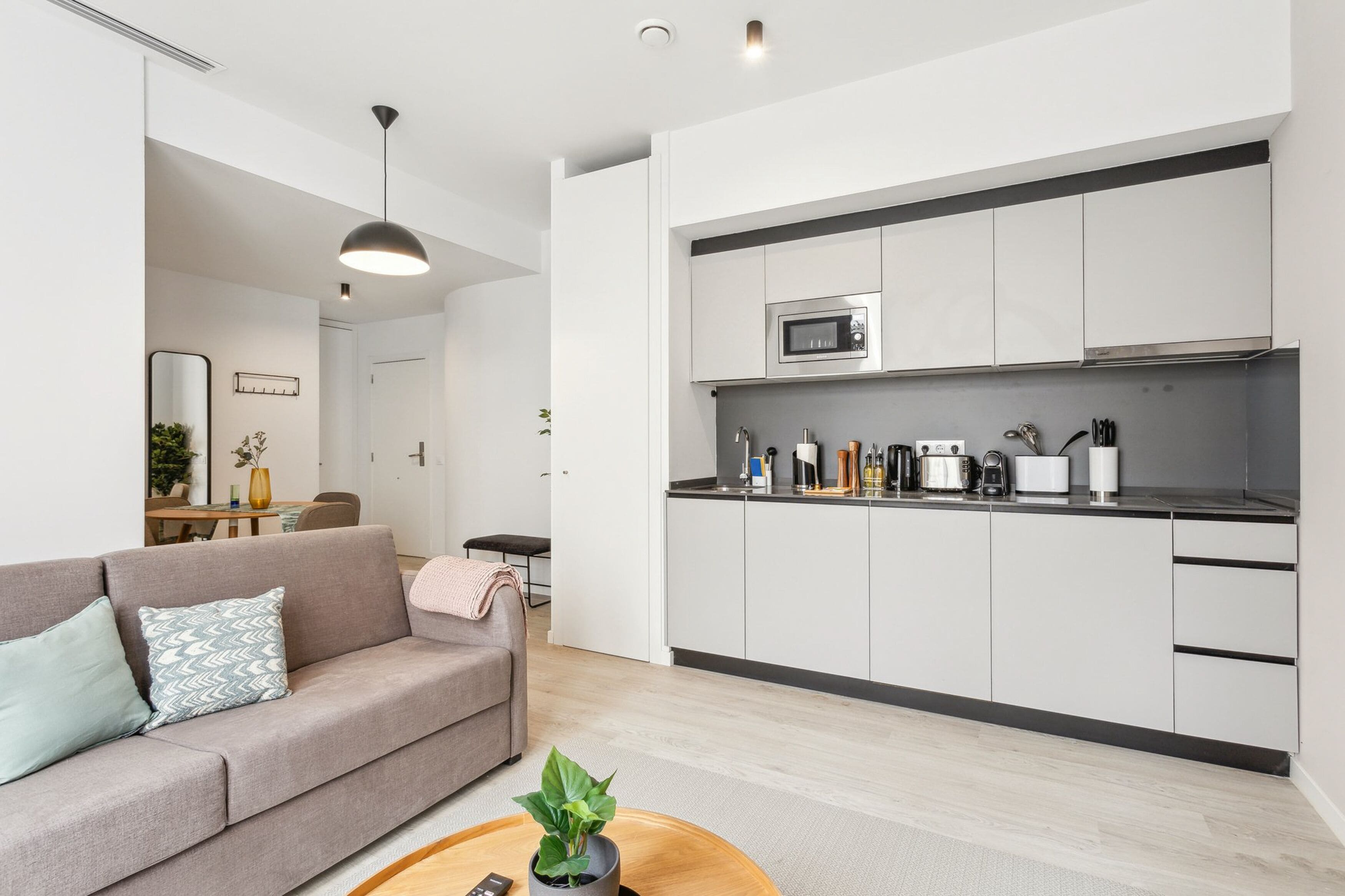 A modern kitchen with white cabinets, a microwave, and various appliances.
