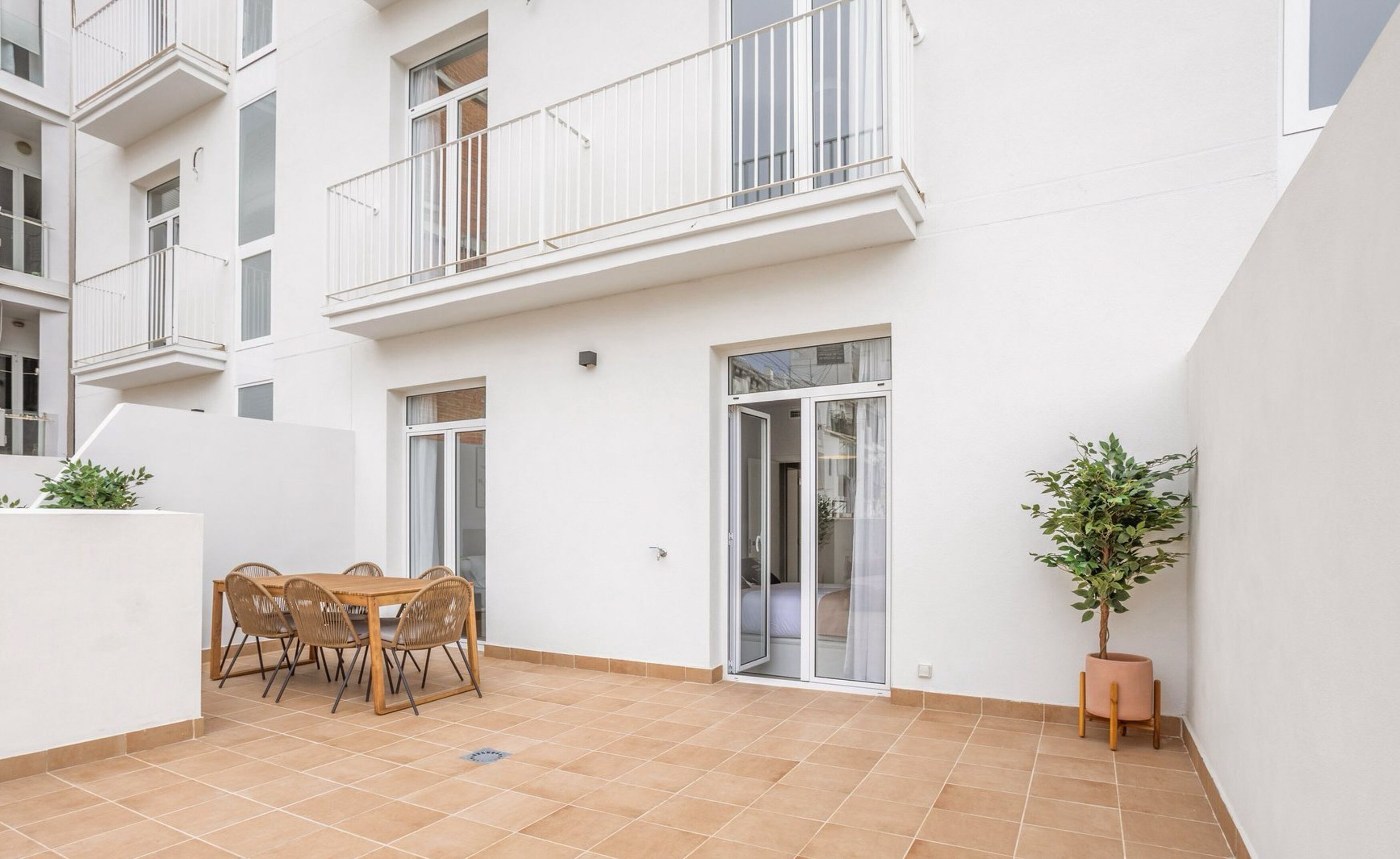 Un apartamento moderno con balcón, un área de comedor con mesa y sillas, y una planta en maceta.
