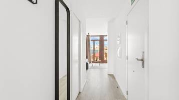 Un pasillo con un espejo a la izquierda, una puerta a la derecha y vistas a un área de estar al aire libre con una mesa y sillas.
