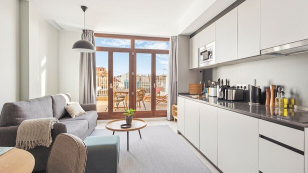 A modern apartment with a living room, kitchen, and a balcony with a city view. - Limehome Valencia Calle de Cadiz (Valencia)