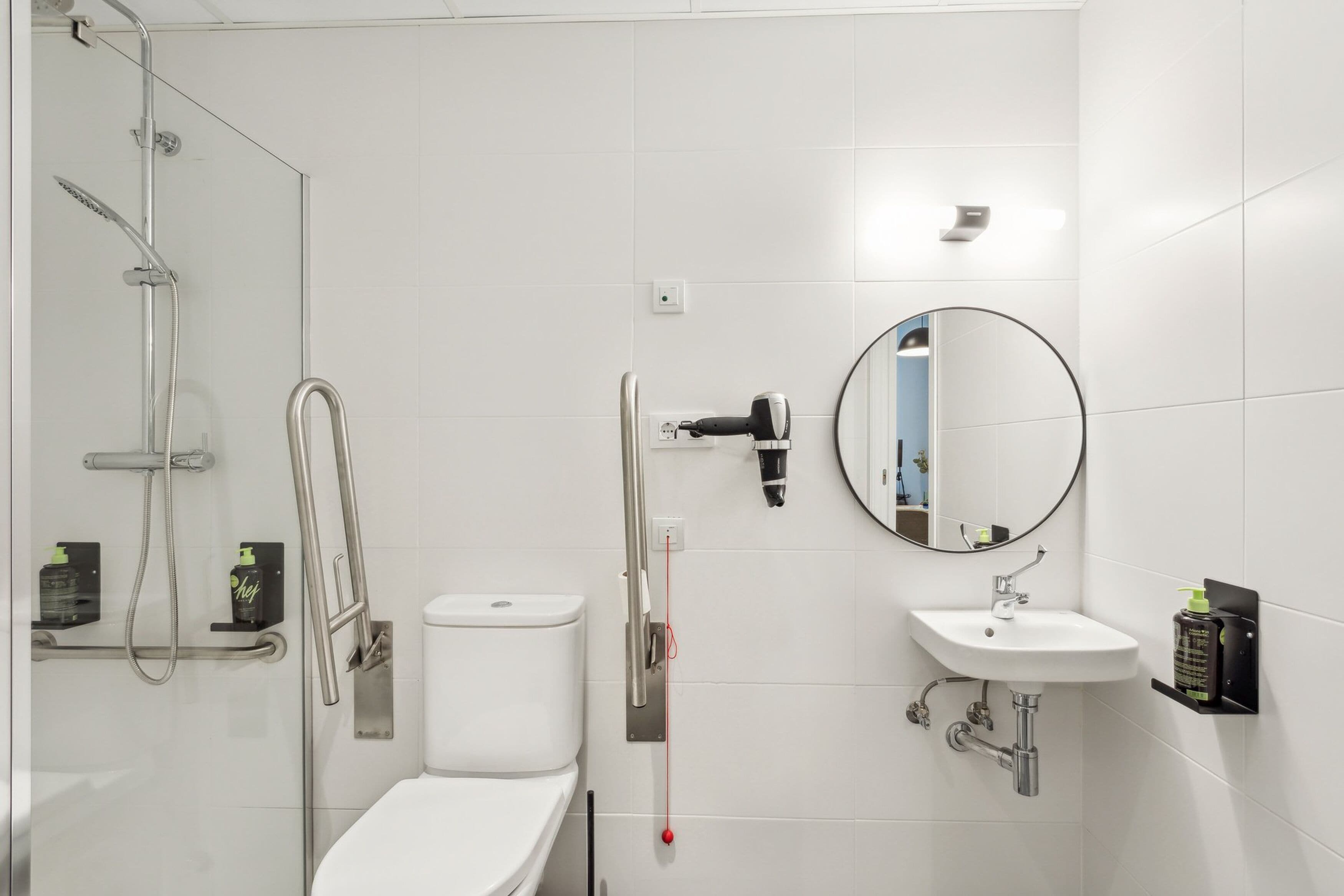 A modern bathroom with a glass-enclosed shower, a toilet, a sink, and a mirror.