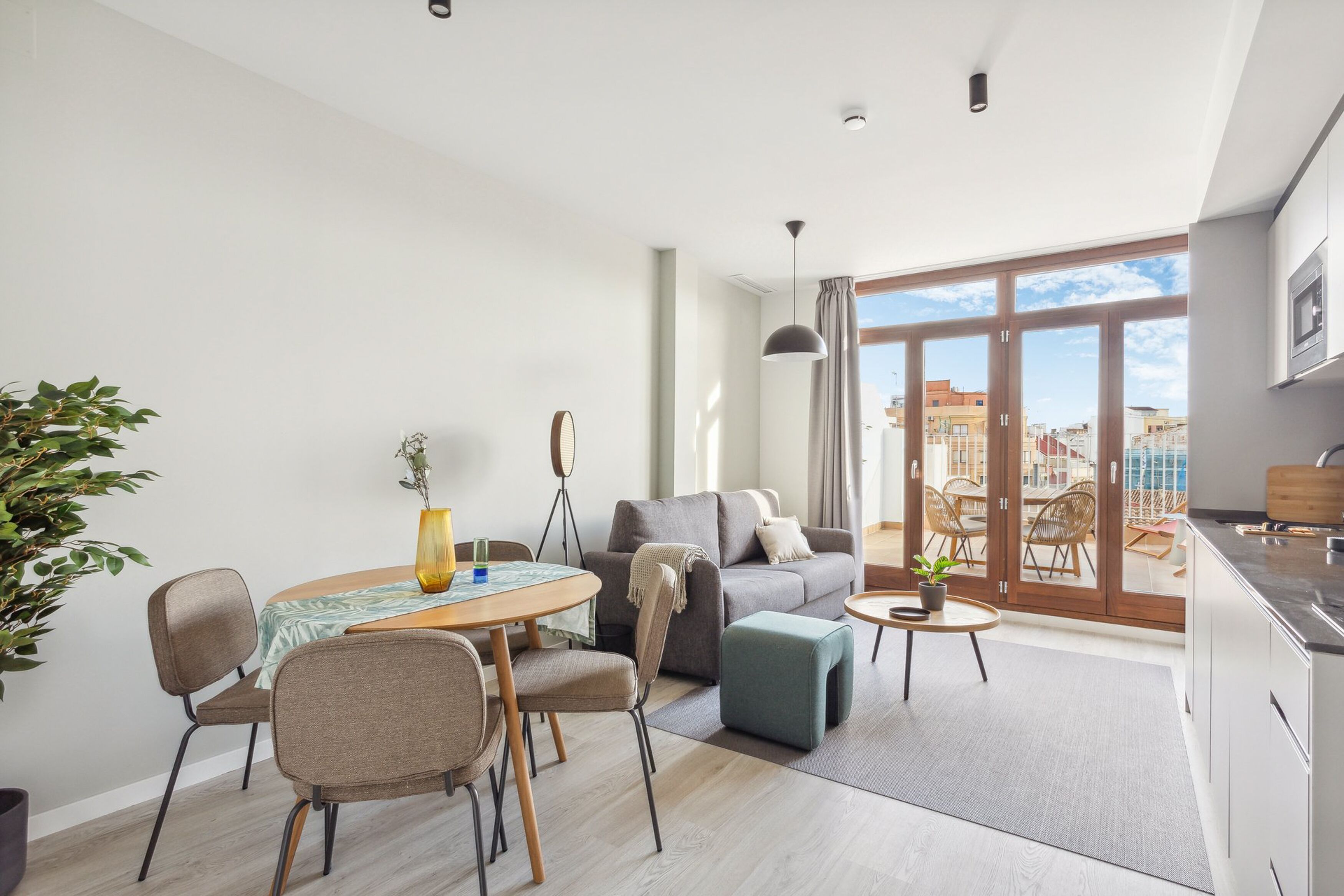Un soggiorno moderno con divano, tavolo da pranzo, sedie e vista sulla città attraverso ampie finestre.