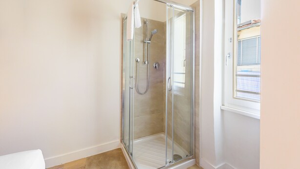 A glass-enclosed shower stall with a handheld showerhead and a handheld faucet. - Novella Contemporary Apartment by Mmega (Florence)