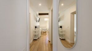A hallway with white walls, wooden flooring, and a mirrored wall on the right. There are white shelves on both sides of the hallway. - Novella Contemporary Apartment by Mmega (Florence)