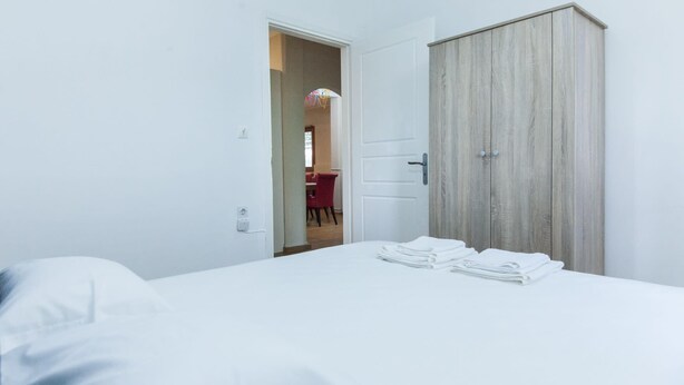 Ett hotellrum med en säng, en garderob och en dörr som leder till ett annat rum.