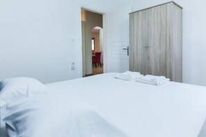 A hotel room with a bed, a wardrobe, and a door leading to another room. - Family Friendly Comfort 3 Bd in Kifisia (Kifisia)