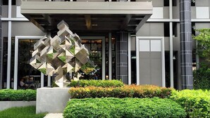 A modern building with a geometric sculpture in the foreground, surrounded by well-maintained greenery.