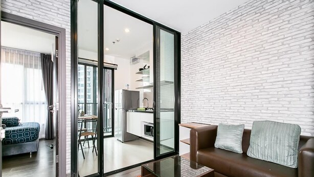 A modern living room with a glass partition, a brown leather sofa, and a glass coffee table.