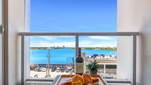 En balkong med utsikt över havet, en flaska vin och ett fat med bröd och ett glas.