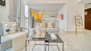 A modern living room with a sofa, a coffee table, and a painting on easel.