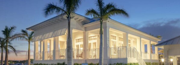 A large, white, two-story house with a covered porch, palm trees, and a pool. - 4BR Villa w/ Private Pool & Gym Access (Key Largo)