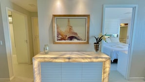 A modern bedroom with a large bed, a bedside table with a vase, and a framed picture of the Eiffel Tower on the wall. - Golf Ville Resort (Aquiraz)