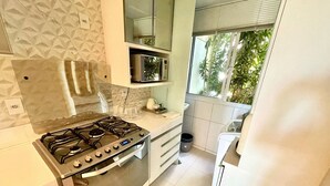 Una cocina moderna con estufa a gas, horno, microondas y una ventana con vistas a zonas verdes.
