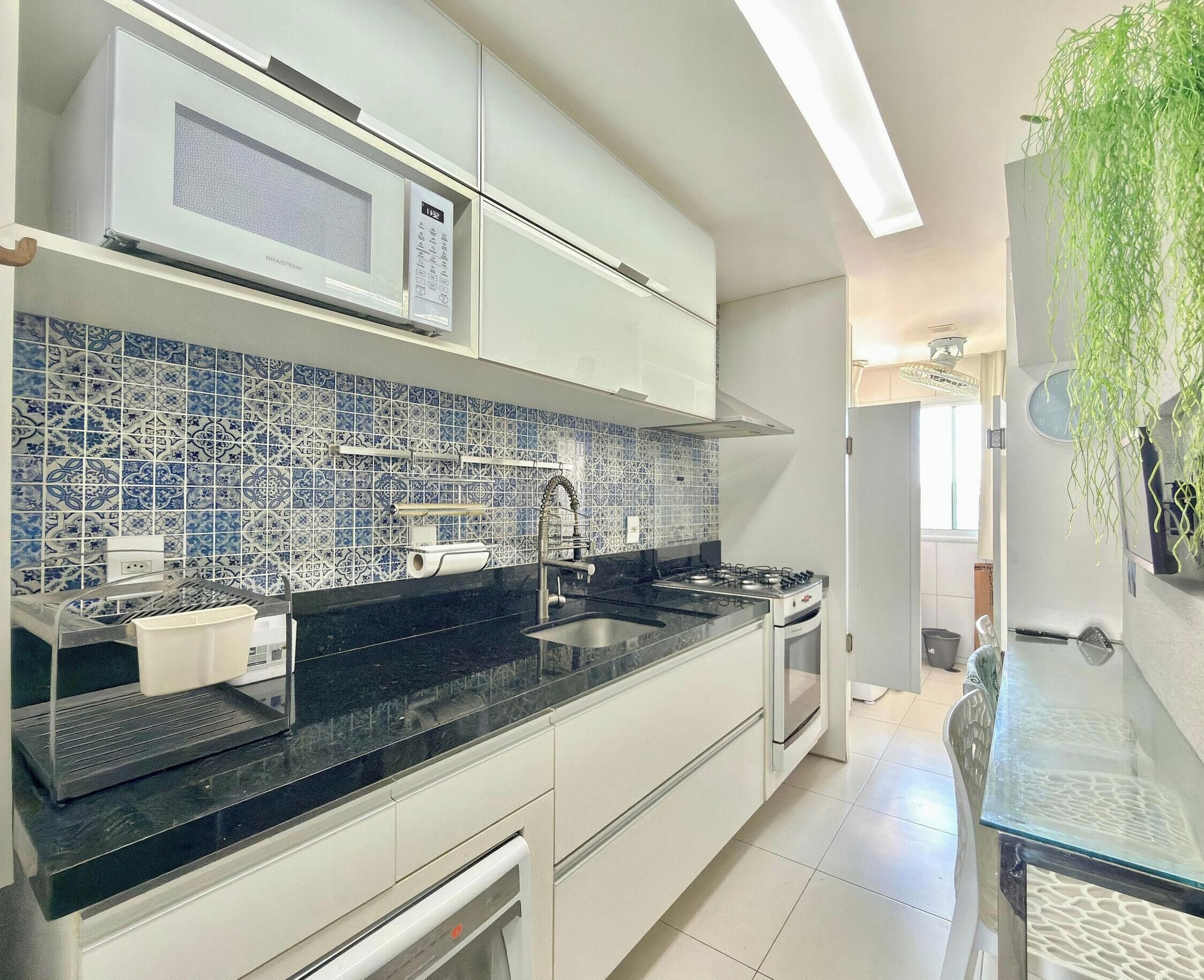 A modern kitchen with white cabinets, a black countertop, a microwave, and a gas stove.