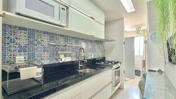 A modern kitchen with white cabinets, a black countertop, a microwave, and a gas stove.