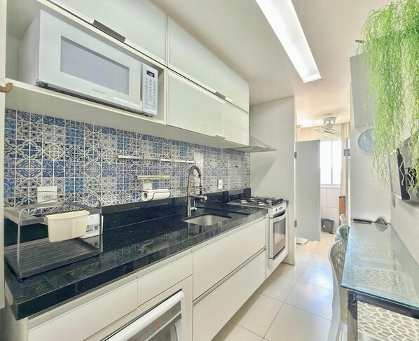 A modern kitchen with white cabinets, a black countertop, a microwave, and a gas stove.