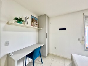 A small, clean room with a white desk, a blue chair, and a white wardrobe. - Golf Ville Resort (Aquiraz)