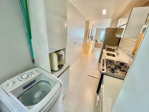 Cocina compacta con estufa a gas, lavadora y una pequeña encimera.