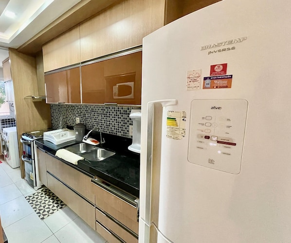 A kitchen with a refrigerator, stove, sink, and microwave.