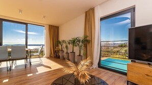 A modern living room with a large window, a dining area, and a TV. - Dalmatian Oasis Luxury Villa (Kaštel Lukšić)