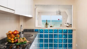 Una cocina con vistas al mar, una botella de champán y una cesta de frutas.