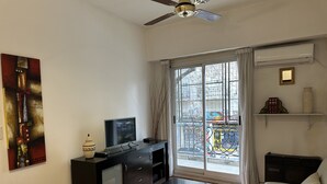 Un salon comprenant un canapé, une table basse, un téléviseur et un ventilateur de plafond.