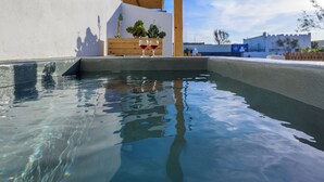 A swimming pool with clear water, wooden pergola, and potted plants. - Athiri Luxury Suites Perivolos (Santorini)